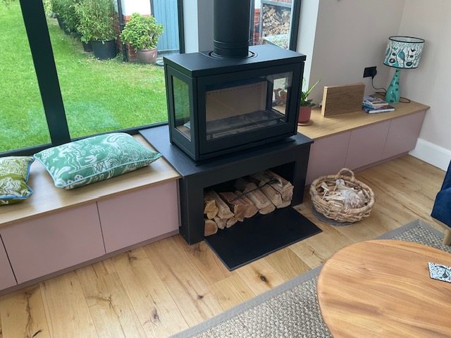 The three-sided stove on a bespoke steel bench with integral log store