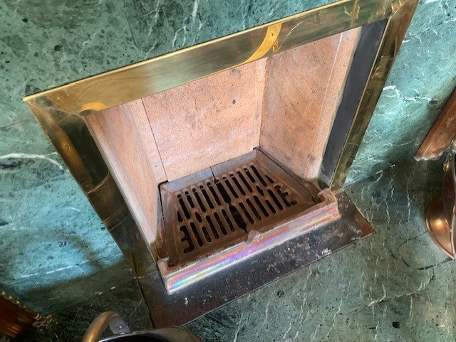 A second fireplace on the property, showing the new grate and clay back set behind the brass frame.