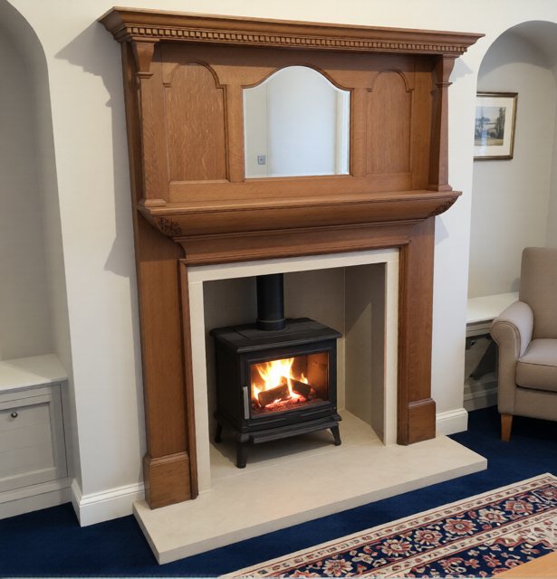 Restored Edwardian timber fireplace surround with a wood burning stove