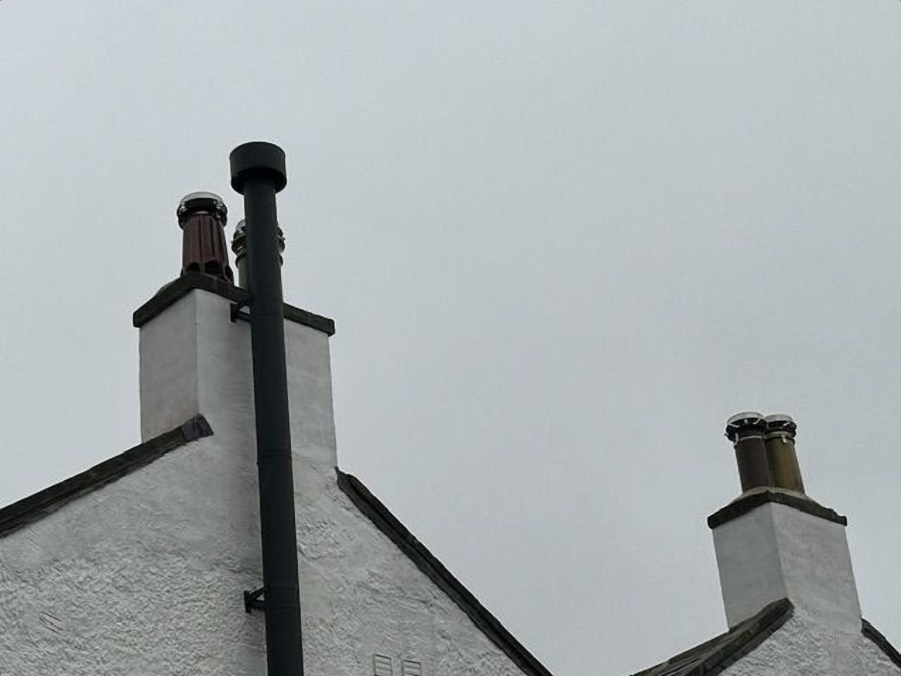 The powder coated twin wall flue rising beside the original chimney stack
