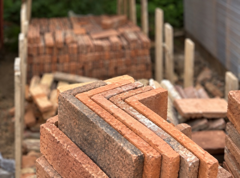 Individual reclaimed brick slips cut into L-shaped corners for a fireplace chamber