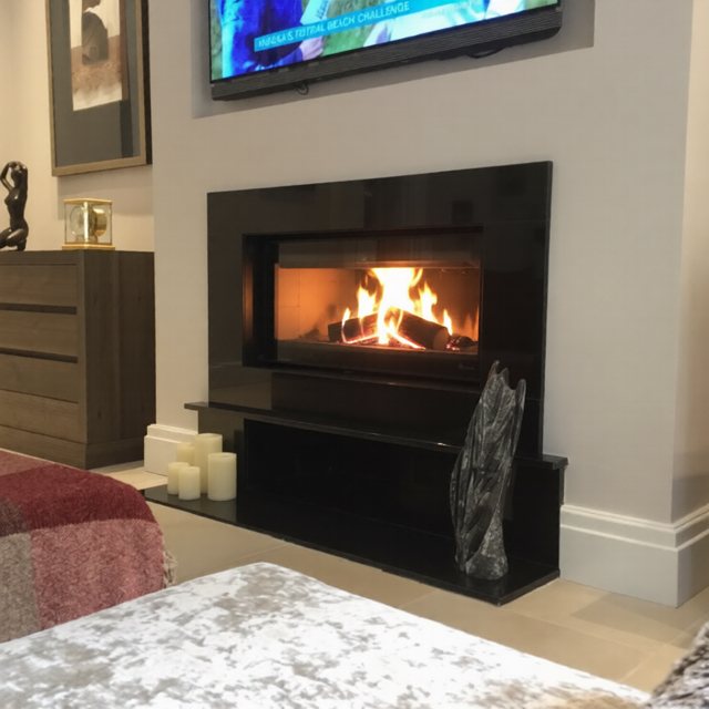 The finished media wall from the side, TV recessed above the fire with the log store below