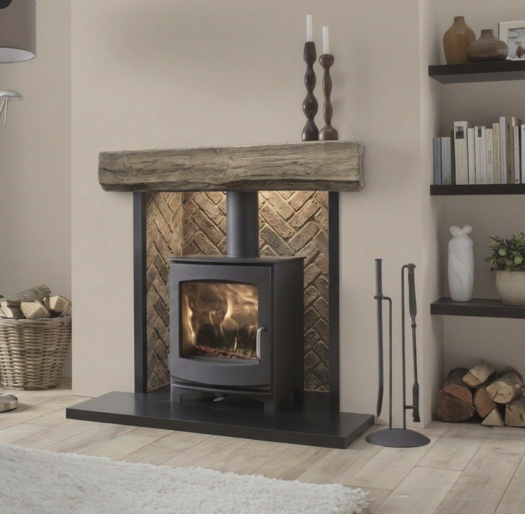 A wood burning stove set in a herringbone brick chamber with an oak beam mantel
