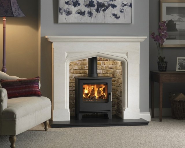 The Eaton Semiridgio limestone fireplace with a Tudor arch and hand-finished foot blocks
