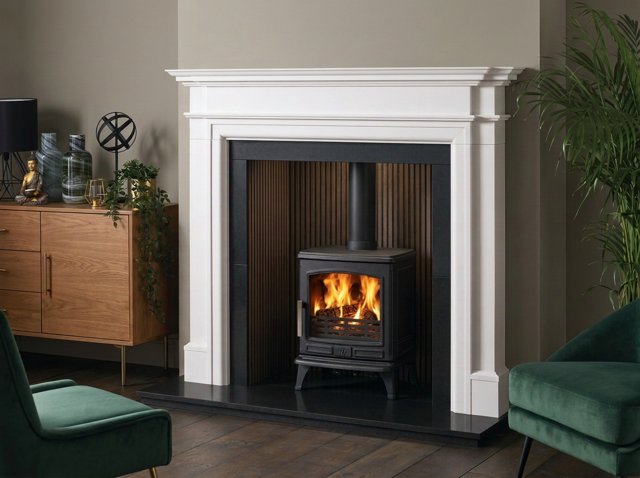 A stone hearth beneath a wood burning stove in a fireplace surround